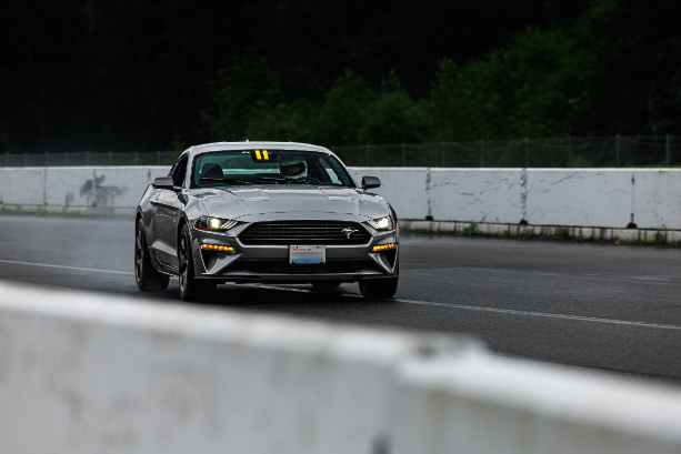 Rob driving a mustang on a wet racetrack at Pacific Raceways